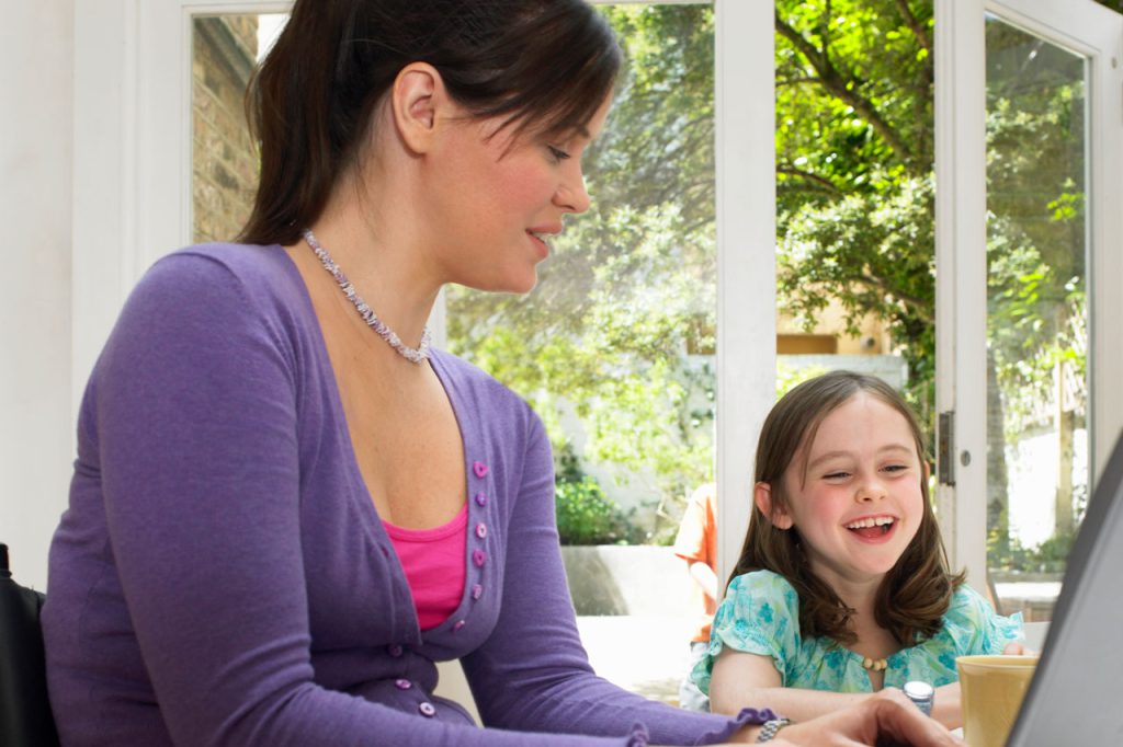 A mother with a disability looking at a laptop together with her daughter