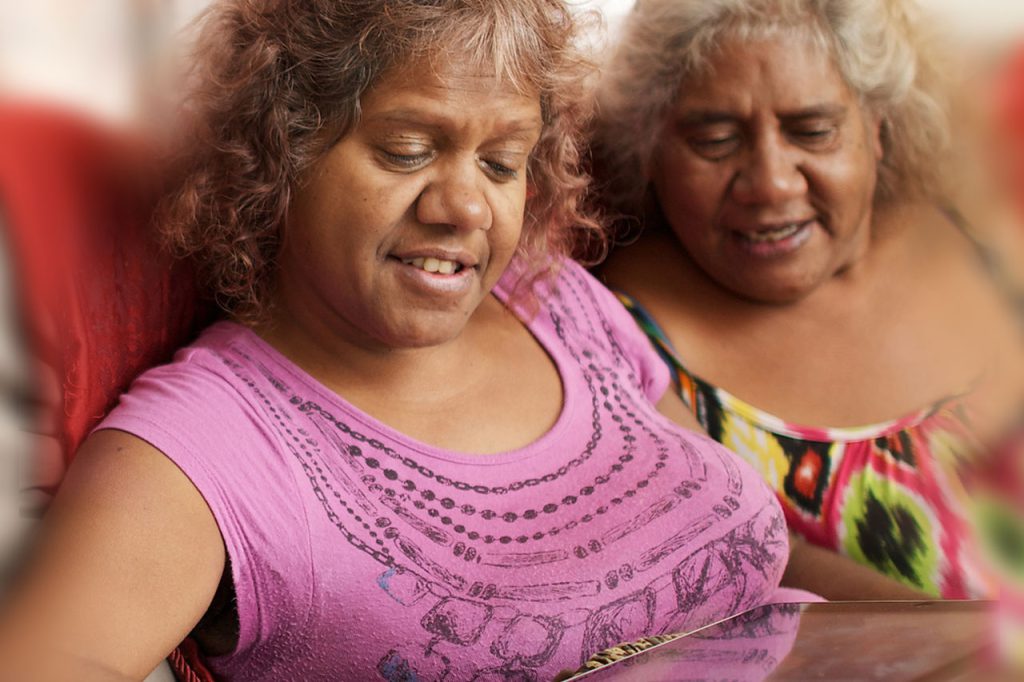 Two indigenous women looking at a tablet device together