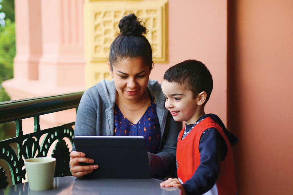 An indigenous mother and child looking at a tablet device together