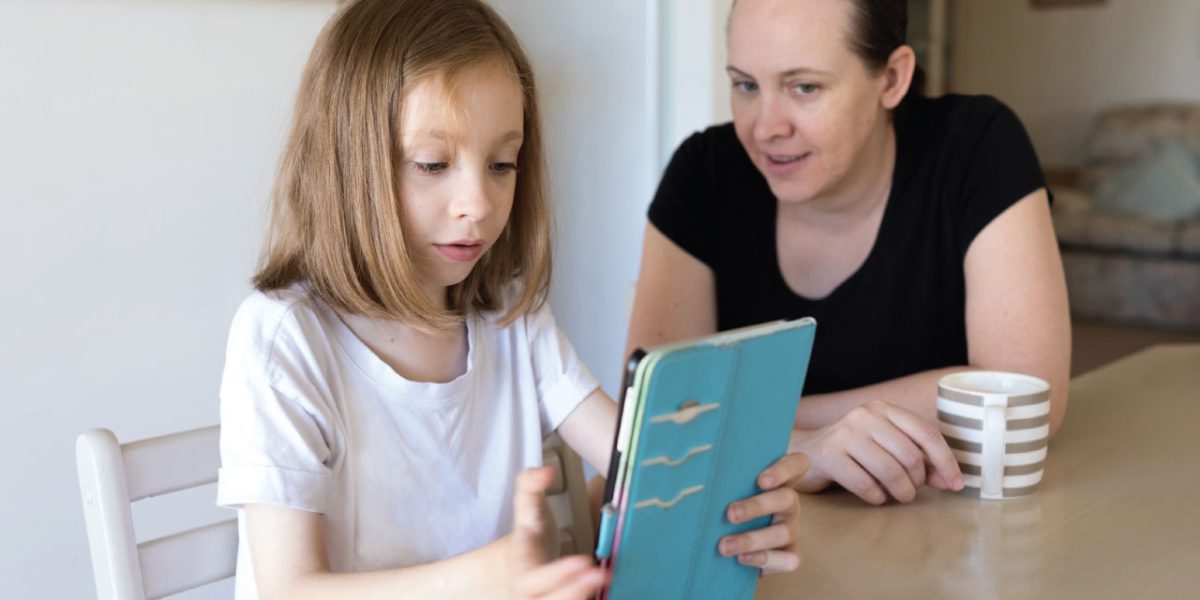 A single mother assisting her daughter using a tablet device