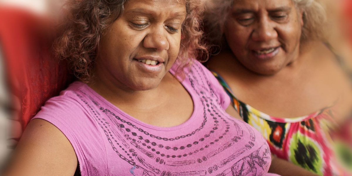 Two indigenous women looking at a tablet device together