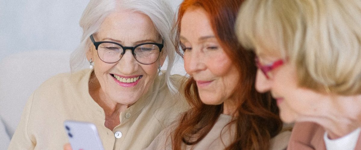 Three older women looking at a smartphone device