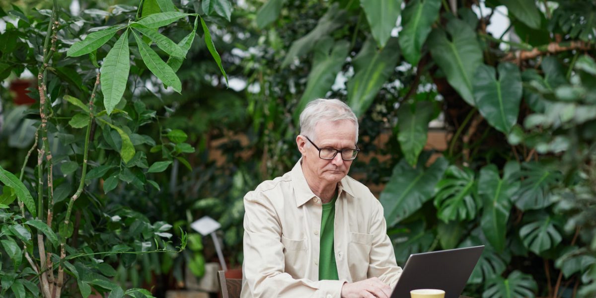 Older man using a laptop outside