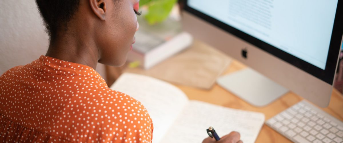 Woman sitting in front of computer studying and reading her notes